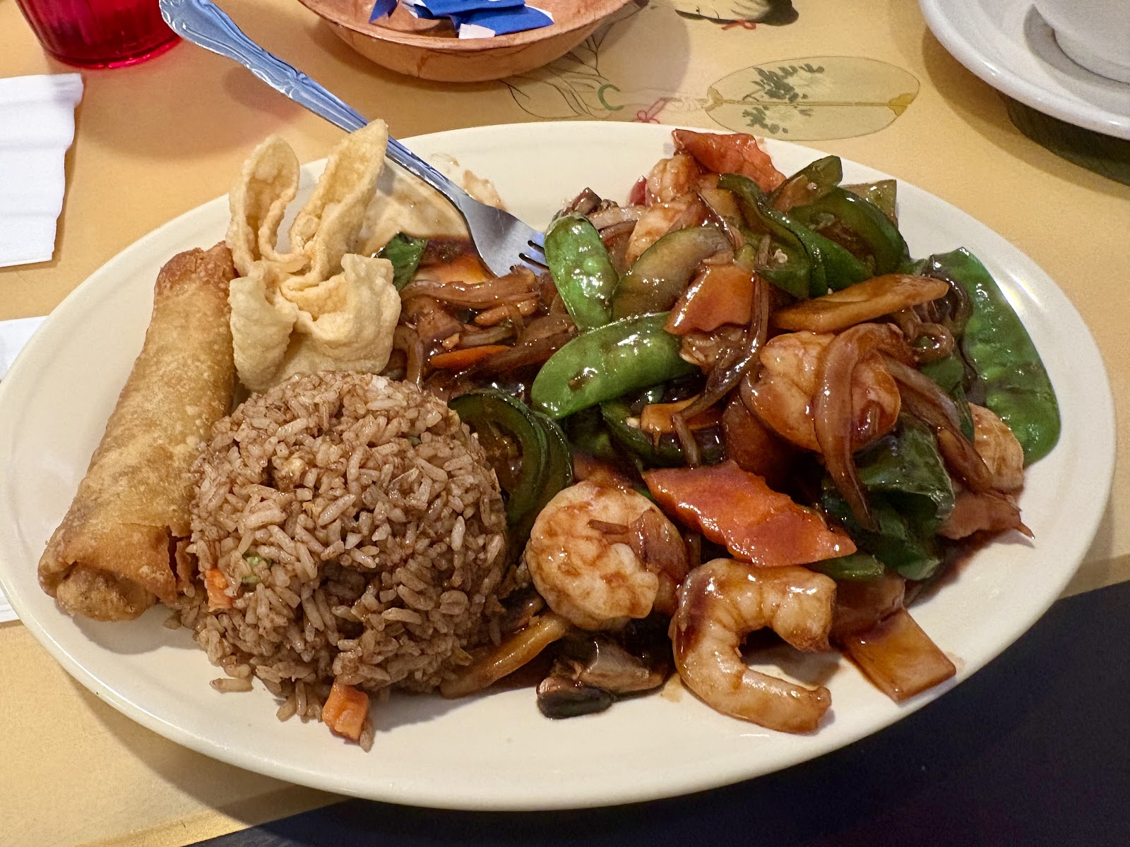 Shrimp stir-fry plate with fried rice and an egg roll